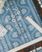 A blue and white patterned Mahjong table with tiles arranged in rows, alongside a scalloped tortoiseshell mahjong racks.