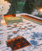 A styled table setting featuring a blue and white floral leatherette mahjong mat and tablecloth, with scalloped tortoiseshell mahjong racks.