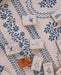 A styled flat-lay of a mahjong game, showing several mahjong tiles with botanical illustrations and two green dice on a cream-colored serpentine pattern leatherette mat with a blue floral serpentine pattern.