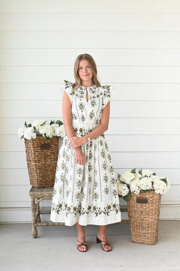 Ivory midi dress with olive green floral block print, flutter sleeves, a keyhole neckline, a smocked waist, and a flowing tiered skirt.