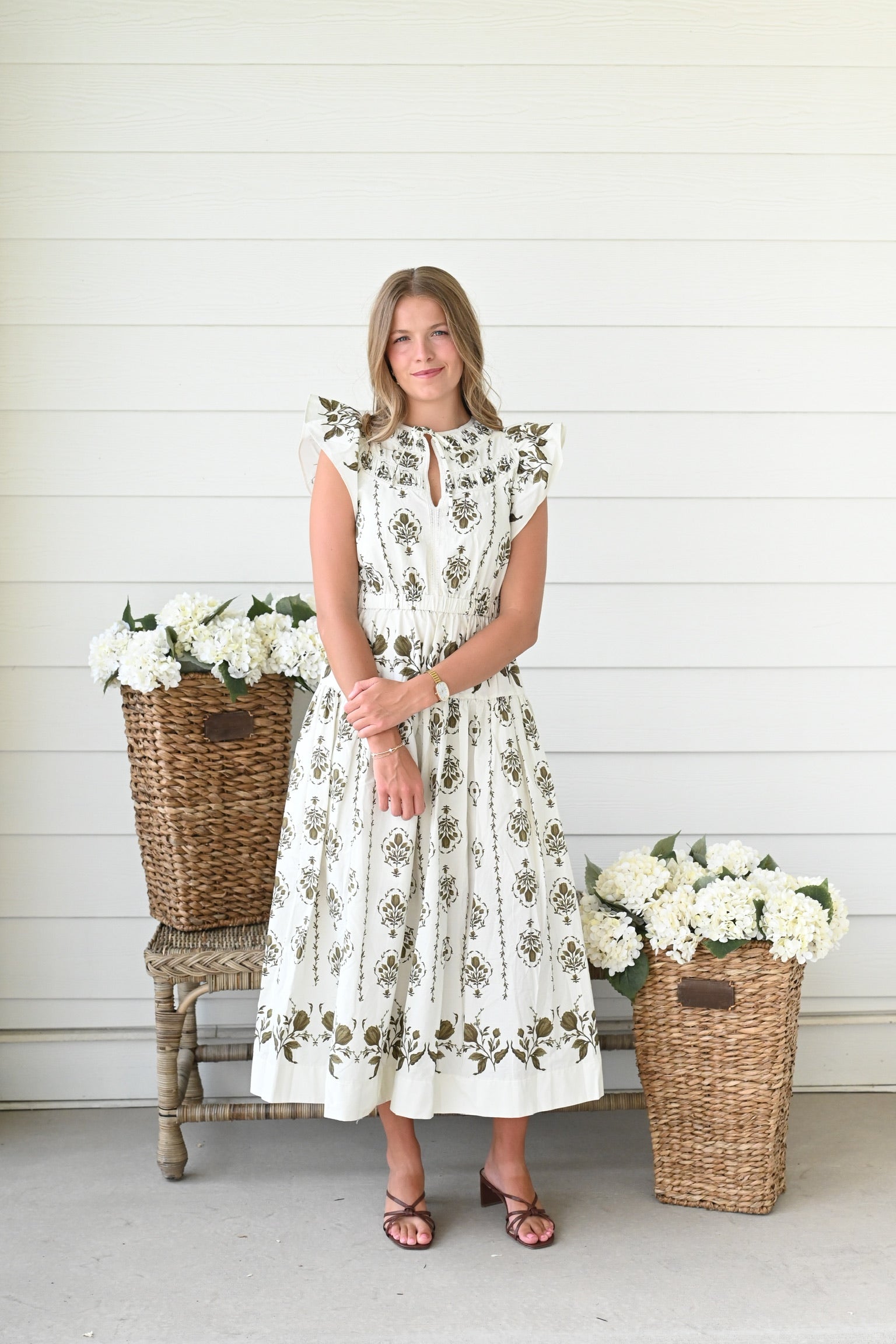 Ivory midi dress with olive green floral block print, flutter sleeves, a keyhole neckline, a smocked waist, and a flowing tiered skirt.