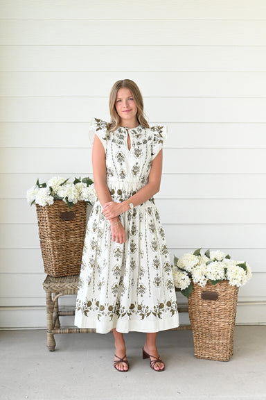 Ivory midi dress with olive green floral block print, flutter sleeves, a keyhole neckline, a smocked waist, and a flowing tiered skirt.